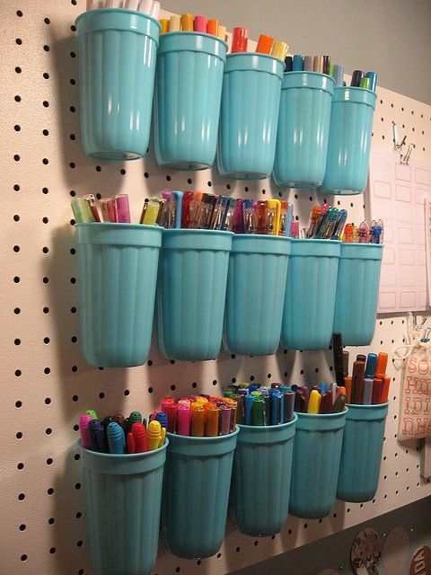 a pegboard with turquoise plastic holders is ideal for storign markers and pencils