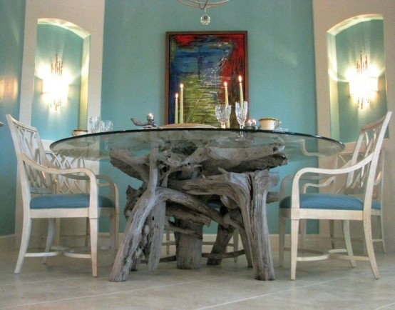 a dining table made of a glass tabletop and a driftwood base for a coastal feel