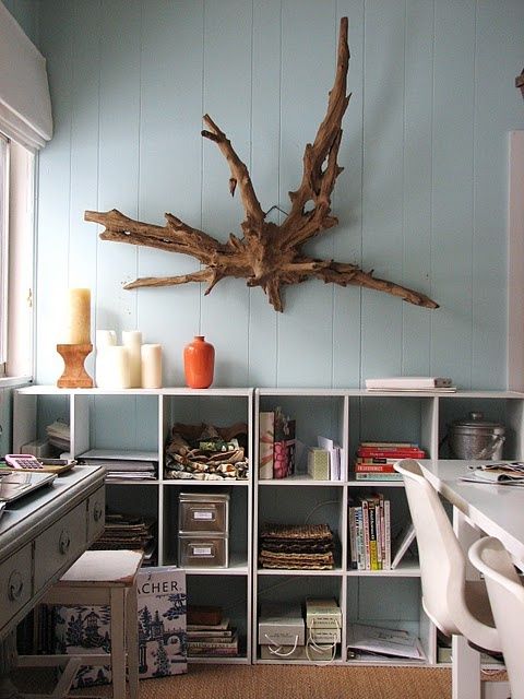 a driftwood artwork placed over a shelving unit for a coastal feel in the space