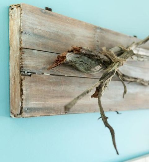 a wooden piece with driftwood attached as a clothes or jewelry hanger or an artwork