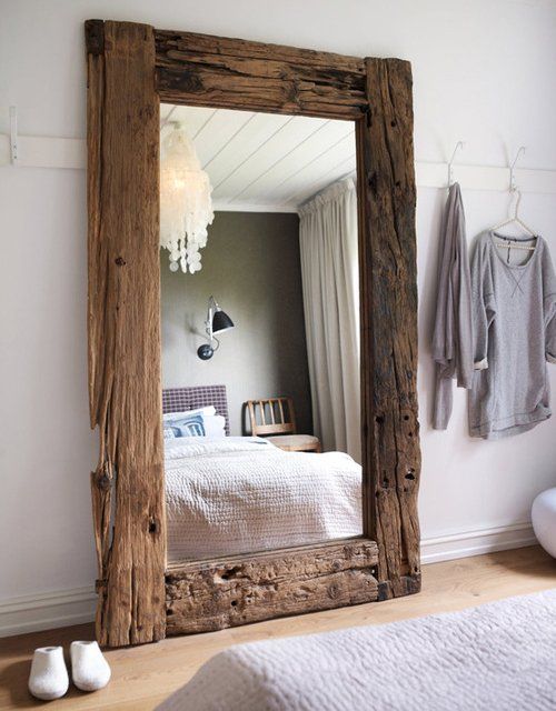 an oversized mirror in a driftwood frame is a stylish idea with practical value for a bedroom