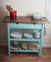 a blue Ikea Forhoja cart with a wooden countertop used in the kitchen for storage of various necessary things