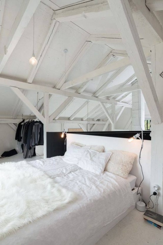 a minimalist loft bedroom with a white bed and bedding and a makeshift closet right here, under the roof