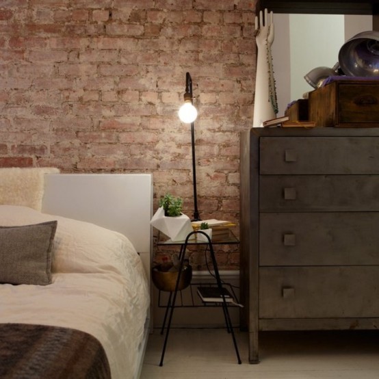 a vintage industrial bedroom is made finished off with an exposed brick wall - it's a perfect decor feature for such a space