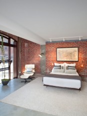 a mid-century modern bedroom with industrial touches – concrete, metal lamps and an exposed brick wall