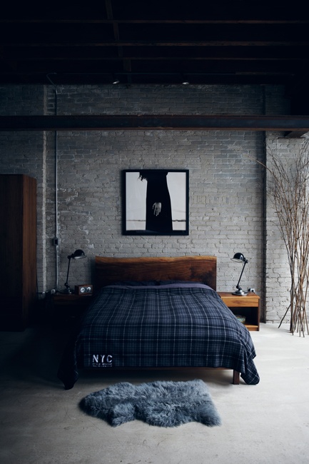 A moody masculine bedroom with a grey brick statement wall and chic mid century modern furniture