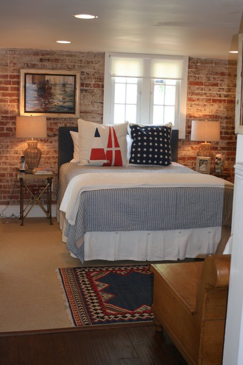 A mid century modern bedroom with a brick wall, printed textiles and wicker and burlap lamps