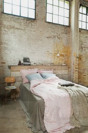 a shahby chic bedroom with a neutral brick wall, a reclaimed wooden bed and some vintage items
