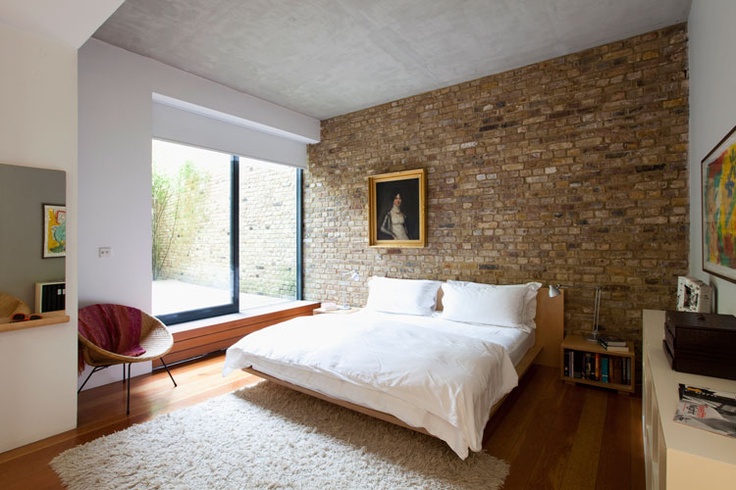 A neutral mid century modern bedroom would have looked more boring and too polished without a brick wall in sandy tones