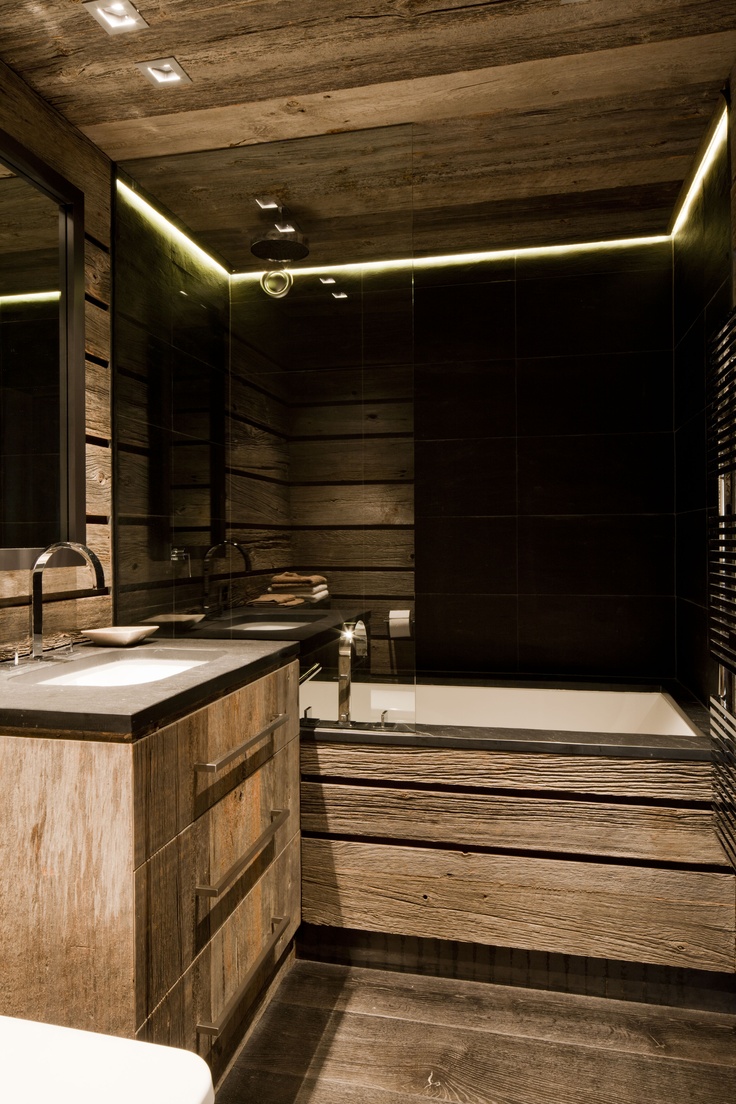 A contemporary chalet bathroom with light stained wood all over, with black tiles, built in lights and a floating vanity