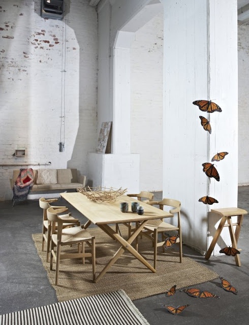 An eclectic space with whitewashed brick walls, double height ceilings, modern wooden and leather furniture and butterflies for decor