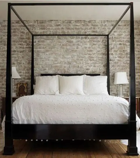A vintage farmhouse bedroom with a whitewashed brick wall for an accent and more eye catchiness and a dark heavy wooden bed
