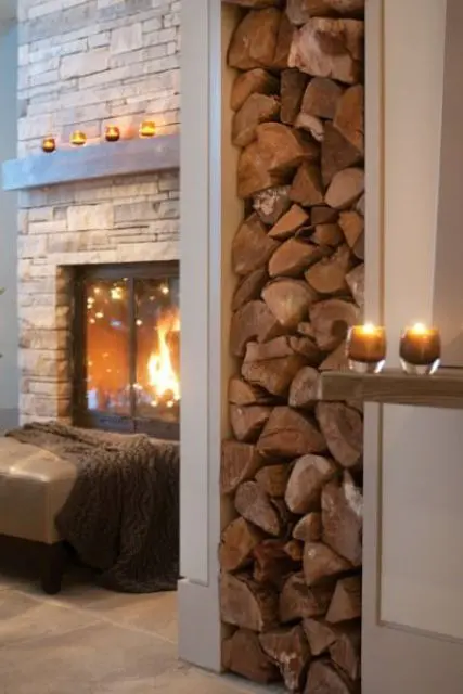 A welcoming space with a built in fireplace clad with faux stone, a leather ottoman with a blanket and some candles around