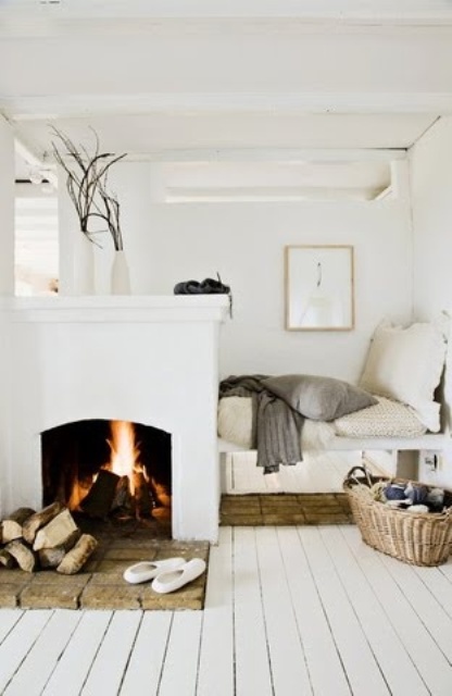 a Scandinavian nook with an open fireplace and firewood plus a small nook to sit in with cushions and pillows is welcoming