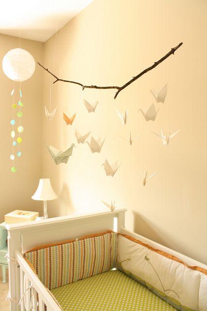 a simple and delicate nursery mobile with a branch and pastel-colored paper cranes is a stylish and dreamy idea