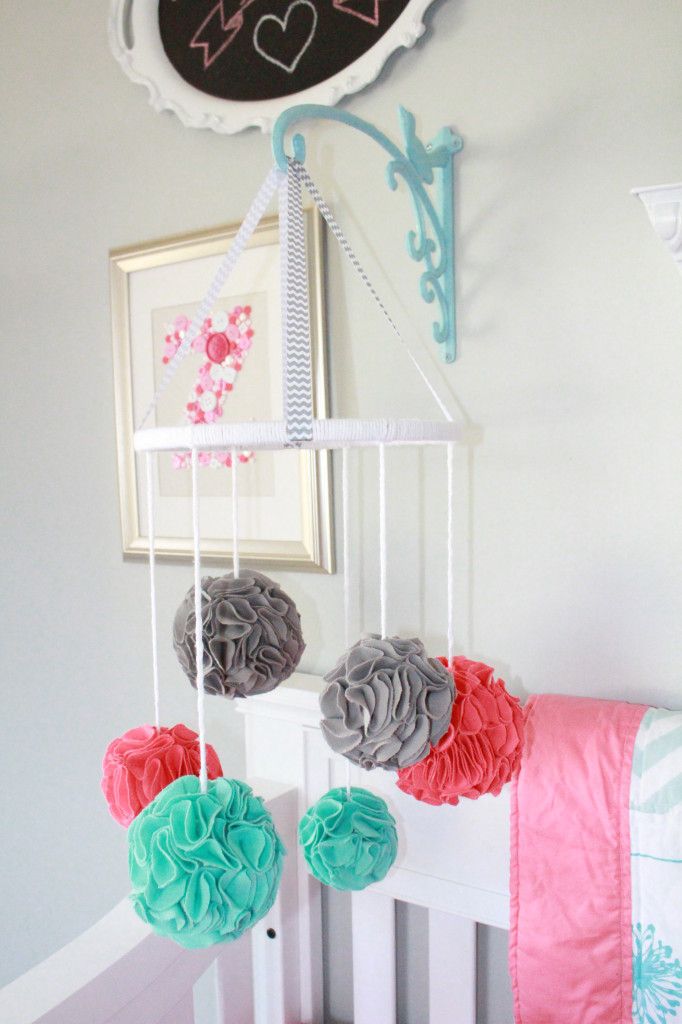 A simple and bold nursery mobile made of colorful felt pompoms can be easily DIYed by you yourself