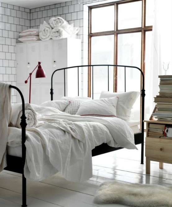 a light-filled bedroom with tiled walls, a metal bed with neutral bedding, a white metal file cabinet for storage, a wooden nightstand with books