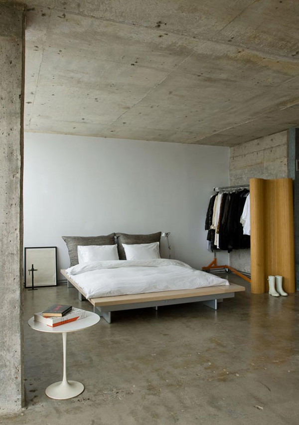 A minimalist meets industrial bedroom with concrete walls, ceiling and floors and ultra minimalist furniture