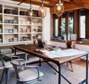 an eclectic home office with industrial touches, with wooden beams, built-in shelving units, an industrial metal and wood desk and metal chairs