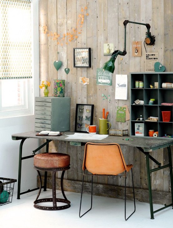 an industrial home office with reclaimed wood walls, a vintage wooden desk, leather chairs and stools, a metal sconce