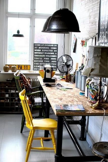 a Nordic industrial home office with a wooden desk, vintage metal pendant lamps, mismatching colorful chairs and some signage