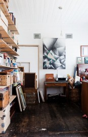 a mid-century modern home artist studio with open shelves, baskets for storage, desks and tables, ledges and lots of artwork
