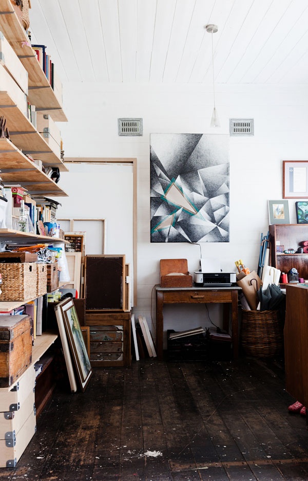 A mid century modern home artist studio with open shelves, baskets for storage, desks and tables, ledges and lots of artwork