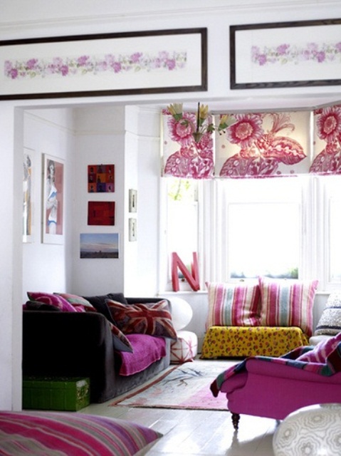 Floral patterned roman curtains and lots of pink textiles create really interesting atmosphere in an all-white living room.