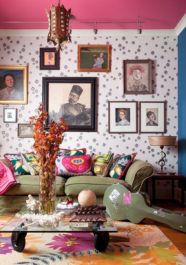 This living room has an extremely imaginative and artistic feel, thanks to the wallpaper's pattern, interesting wall portraits, colorful throw pillows and other antique finds.