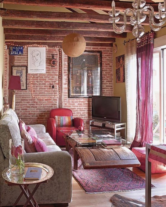 Even though brick walls are more welcome in industrial living rooms, you can play with them in boho environments too. Just make sure to add lots of feminine touches and colors. Throw pillows and pink curtains do the job here.