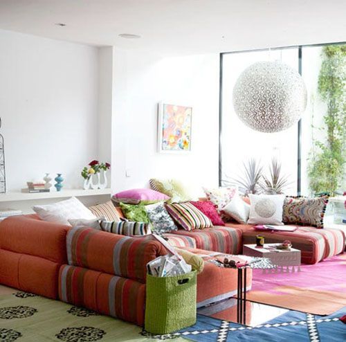 Spacious sofa with lots of throw pillows in colorful patterns is the first thing you should consider designing a boho lounge area.