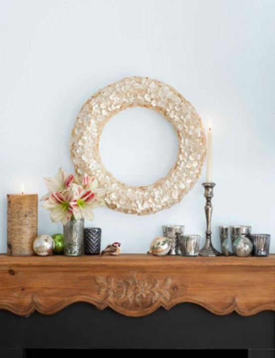 a simple Christmas mantel with a sequin wreath, mismatching mercury glass candleholders, blooms and Christmas ornaments