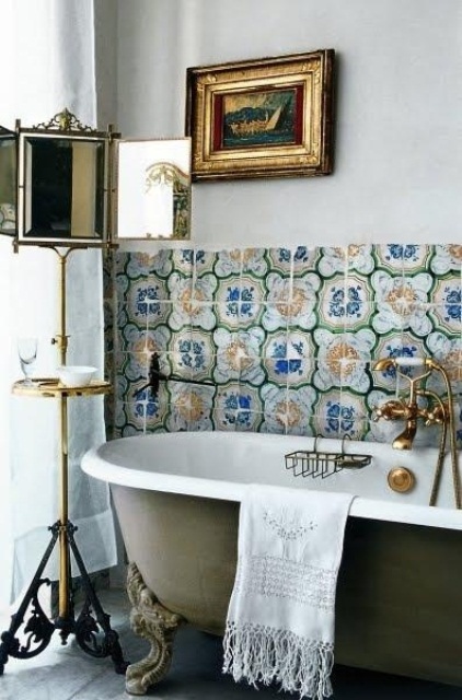 a green bathtub, catchy bright tiles for the backsplash, a mirror on a stand and a sea artwork