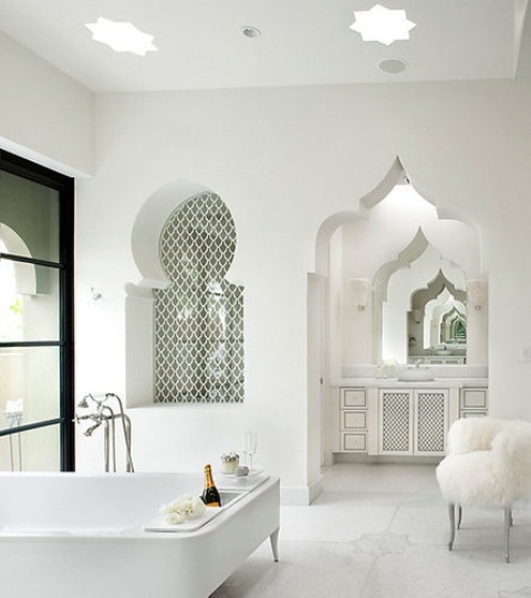 a pure white bathroom with a carved doorway, an arched tiled niche, a carved vanity and a modern chair