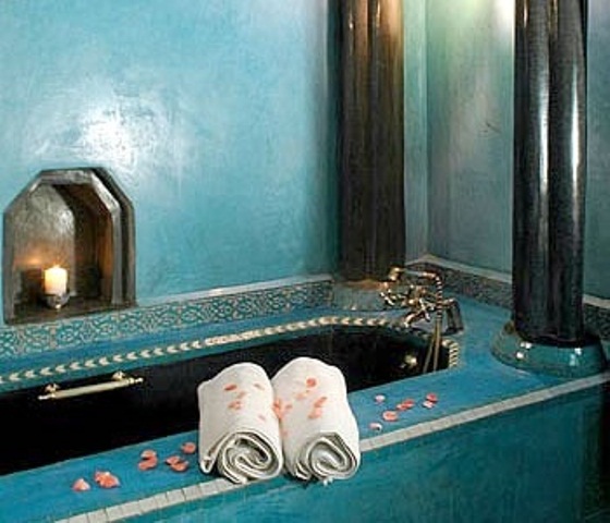 a turquoise bathroom with a tile clad bathtub plus a niche with a candle