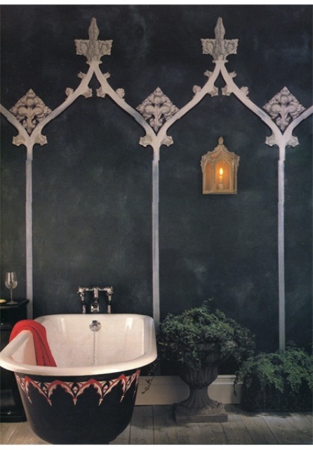 a dark Moroccan bathroom with black walls with patterns, potted greenery and a decorated bathtub