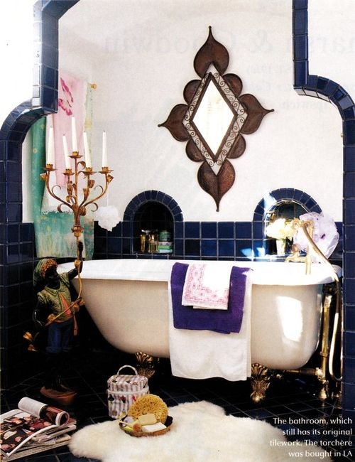 a navy and white tiled bathroom with an ornated mirror, a beautiful candle holder and a faux fur rug