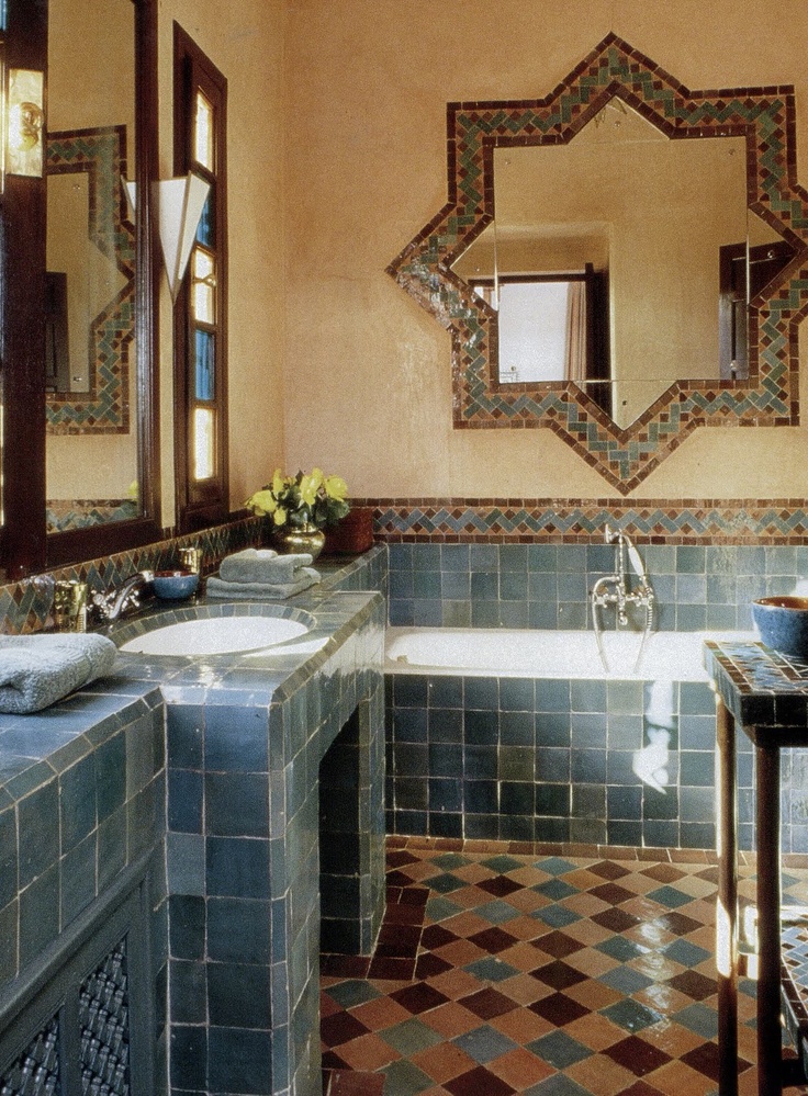 a colorful Moroccan bathroom with a mosaic tile floor, blue tile vanities, a star-shaped mirror