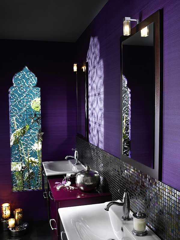 a bright purple bathroom with an arched window, a tiled backsplash, laser cut candle lanterns
