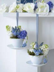 white and purple blooms on the shelf and blooms and moss in mugs hanging down make the kitchen springy