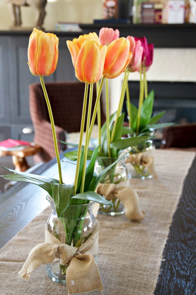 Bright blooms in jars wrapped with burlap and with a burlap table runner make the tablescape spring like