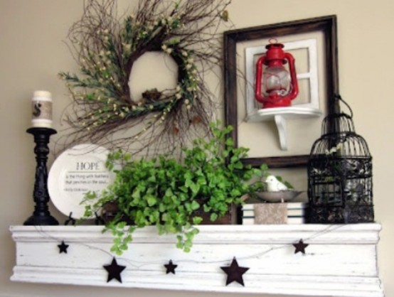 a blooming and greenery wreath over the mantel, potted greenery, a fake bird and a bird cage