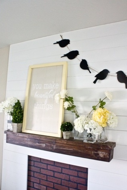 a rustic spring mantel with bloom arrangements and potted greenery, a sign and a bird garland