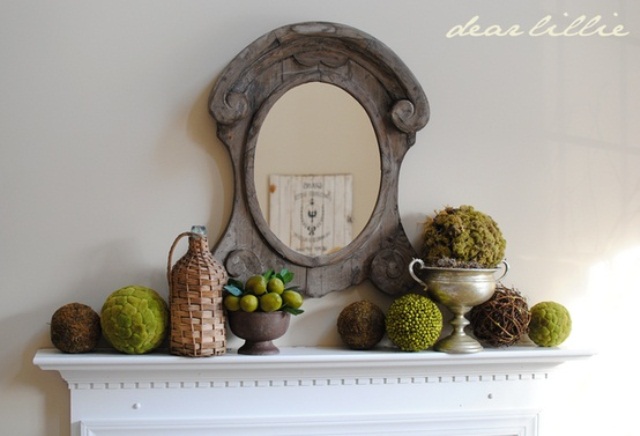 A vintage inspired spring mantel with moss balls, fake fruit arrangement and topiaries