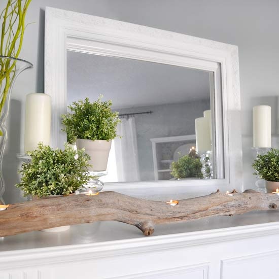 a simple and modern spring mantel with a branch with candles, potted greenery and candles