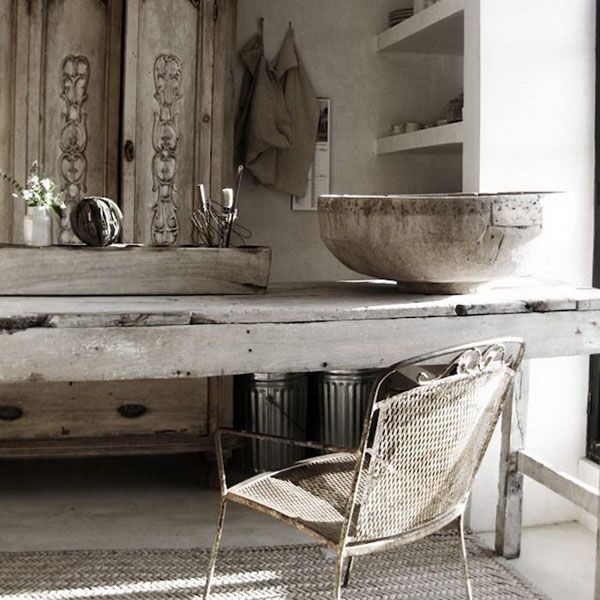 A rough wooden table, a rough stone bowl and a shabby metal chair add a touch of wabi sabi aesthetics to the space