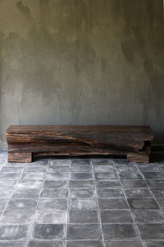 Shabby tiles on the floor and a concrete wall plus a rough wooden slab bench for a wabi sabi entryway