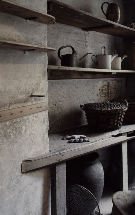 A wabi sabi pantry in wood and stone, with baskets and buckets, a large vase for storage