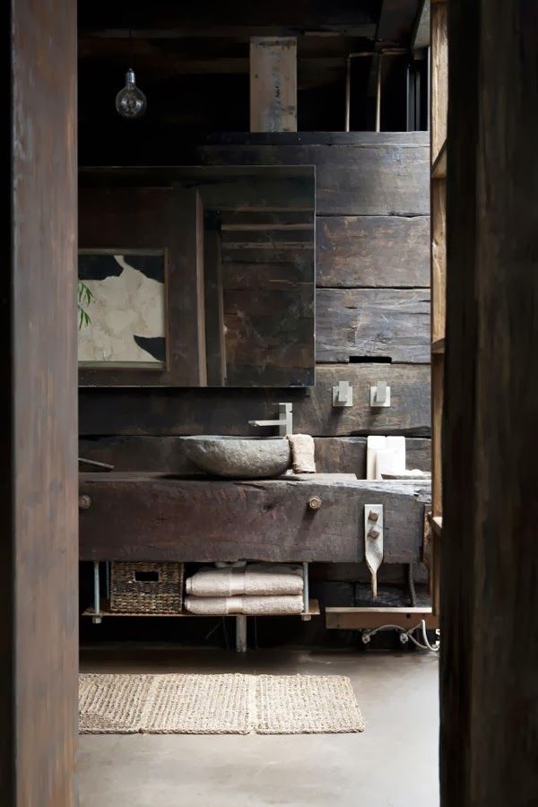 A wabi sabi bathroom with a rough wooden wall, a rough wooden vanity and a stone sink
