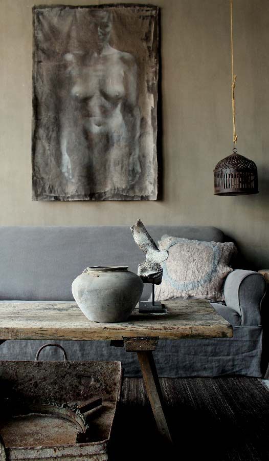 A wabi sabi living room with a pendant lamp, an artwork, a rough wooden coffee table and a metal bathtub
